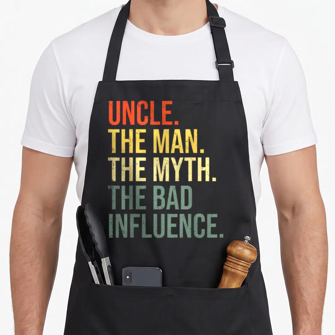 Uncle funcle apron - Stacked distressed text reading UNCLE THE MAN THE MYTH THE BAD INFLUENCE in orange yellow and green — shown on a black cotton canvas apron against a white background