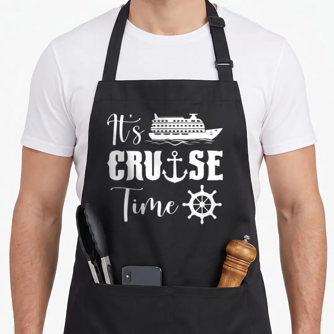 Cruise embroidery apron - White It's CRUISE Time text with ship, anchor, and wheel on black — shown on a black cotton canvas apron against a white background