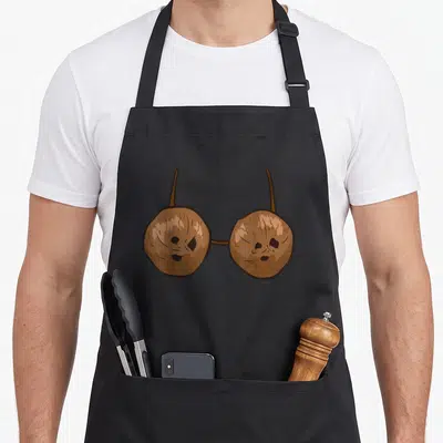 Coconut summer aprons - Two brown cartoon coconut halves connected by straps resembling a bikini top — shown on a black cotton canvas apron against a white background