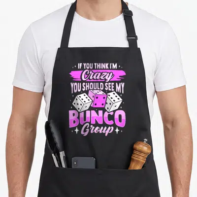 Babe game aprons - Stacked text IF YOU THINK I'M Crazy BUNCO Group with three pink and white dice and scattered stars — shown on a black cotton canvas apron against a white background