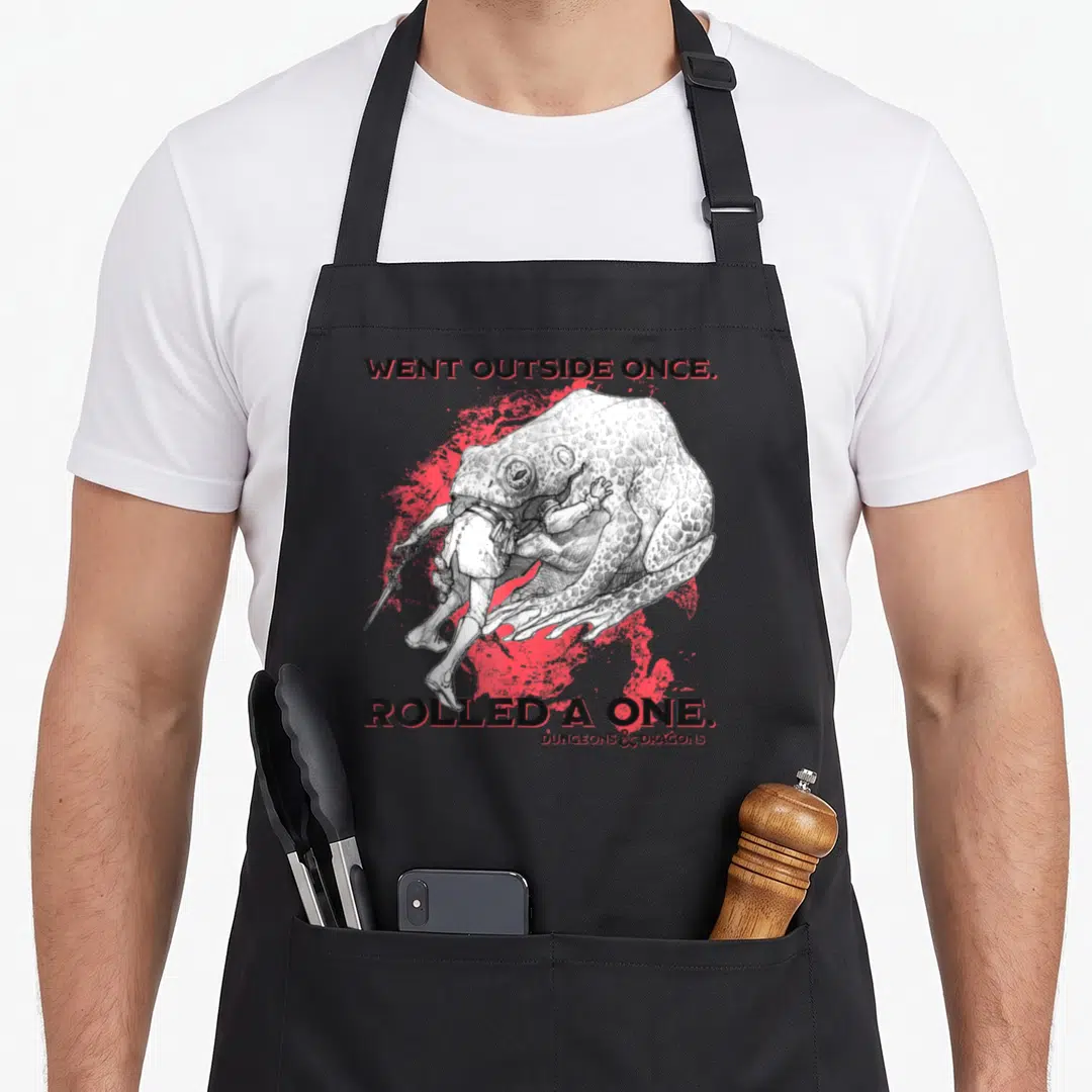 Went dungeon apron - Giant frog eating person with Went Outside Once Rolled A One text on red splatter background — shown on a black cotton canvas apron against a white background