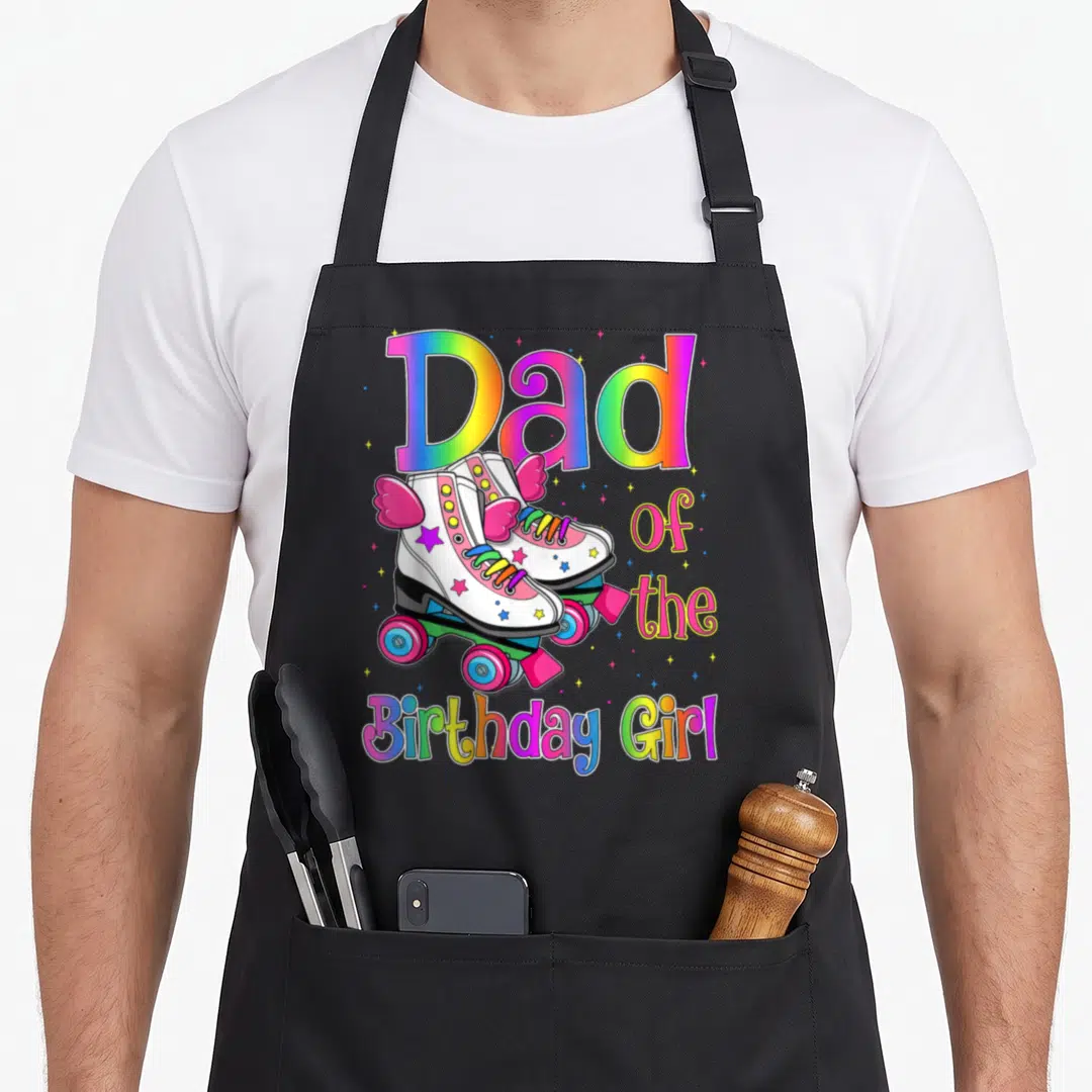 Rolling family cooking aprons - Rainbow Dad of Birthday Girl text with two winged white roller skates and colorful stars — shown on a black cotton canvas apron against a white background