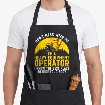 Funny equipment heavy canvas aprons - Excavator graphic with yellow sun and text Don't Mess With Me I Know Best Place — shown on a black cotton canvas apron against a white background