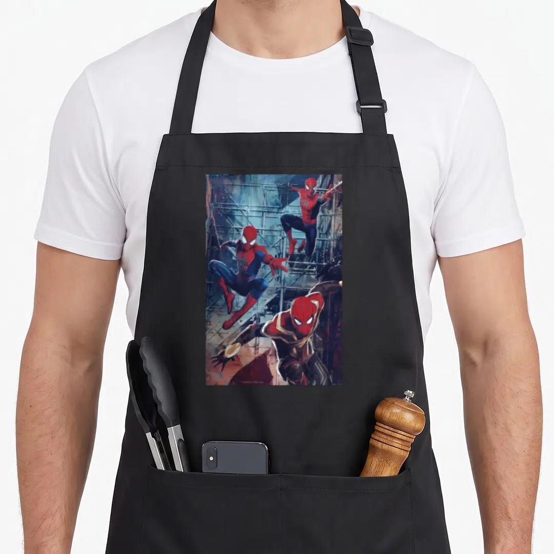 Way jump apron - Three Spider-Man figures in red and blue suits jumping against grey industrial scaffolding background — shown on a black cotton canvas apron against a white background