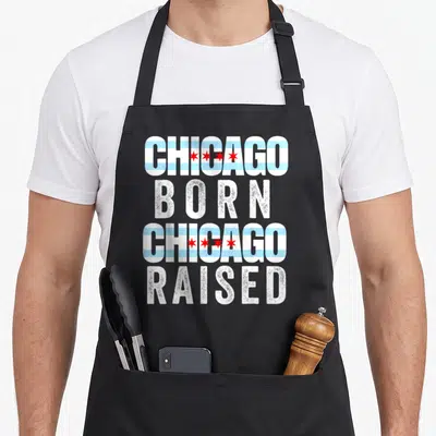 Flag illinois chicago apron - Stacked text Chicago Born Chicago Raised with flag stripes and stars in white blue red — shown on a black cotton canvas apron against a white background