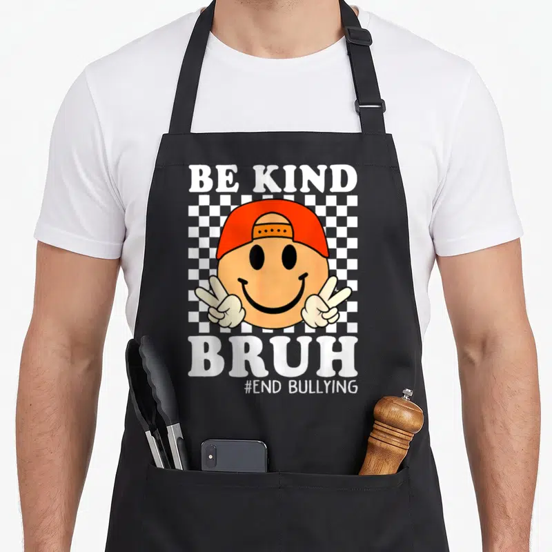 Bruh kind unity day apron - Smiley face orange cap checkerboard BE KIND BRUH #END BULLYING text — shown on a black cotton canvas apron against a white background