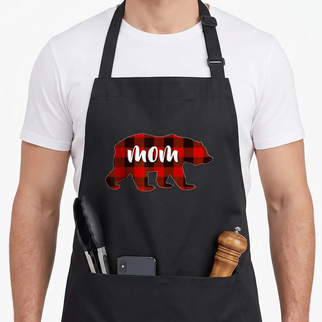 Family buffalo plaid christmas apron - Bear silhouette in red black plaid with white MOM text on torso — shown on a black cotton canvas apron against a white background