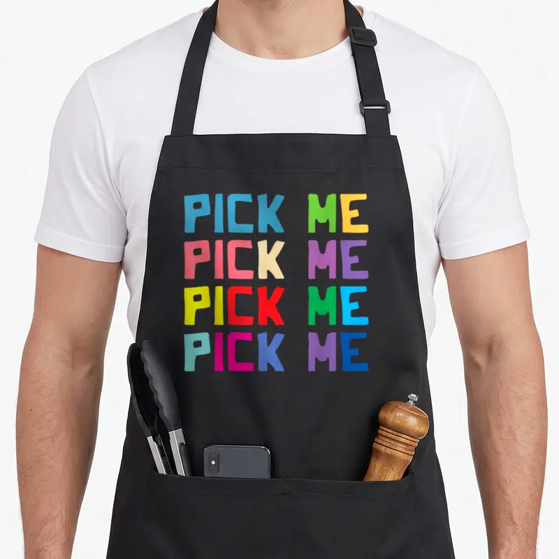 Come colorful aprons - PICK ME text repeated four times in blue green yellow pink purple and red block letters — shown on a black cotton canvas apron against a white background