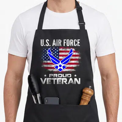 Air american flag apron - U.S. Air Force symbol over distressed flag with Proud Veteran text and stars — shown on a black cotton canvas apron against a white background