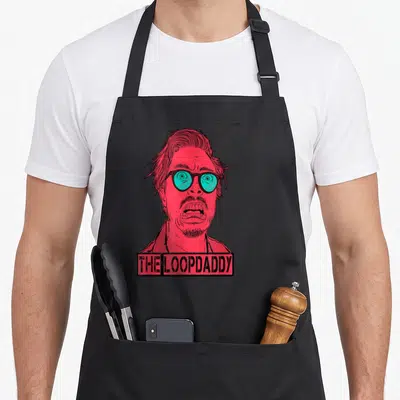 Jazz funky apron - Red line art man with teal glasses above THE LOOPDADDY text box — shown on a black cotton canvas apron against a white background