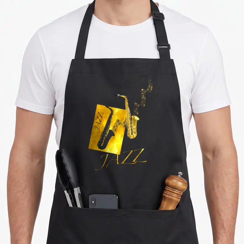 Jazz world music apron - Gold saxophone with musical notes and JAZZ text on black background — shown on a black cotton canvas apron against a white background