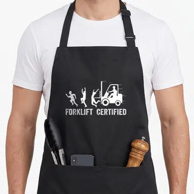 Driver forklift guy apron - White forklift chasing three running people with text forklift certified below — shown on a black cotton canvas apron against a white background