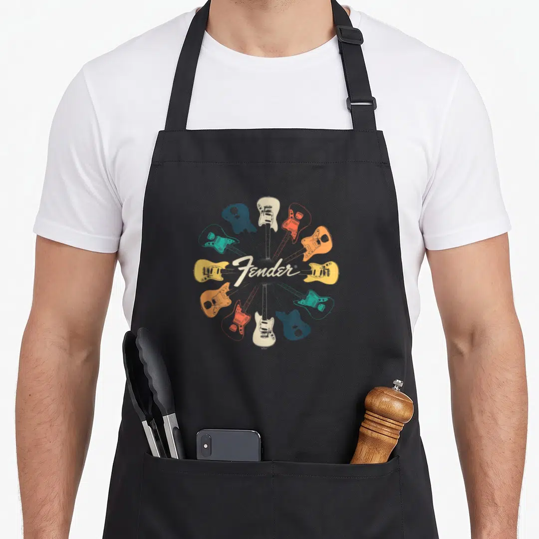 Kaleidoscope fender apron - Ten electric guitars in radial circle with Fender script in blue, orange, red, cream, white — shown on a black cotton canvas apron against a white background
