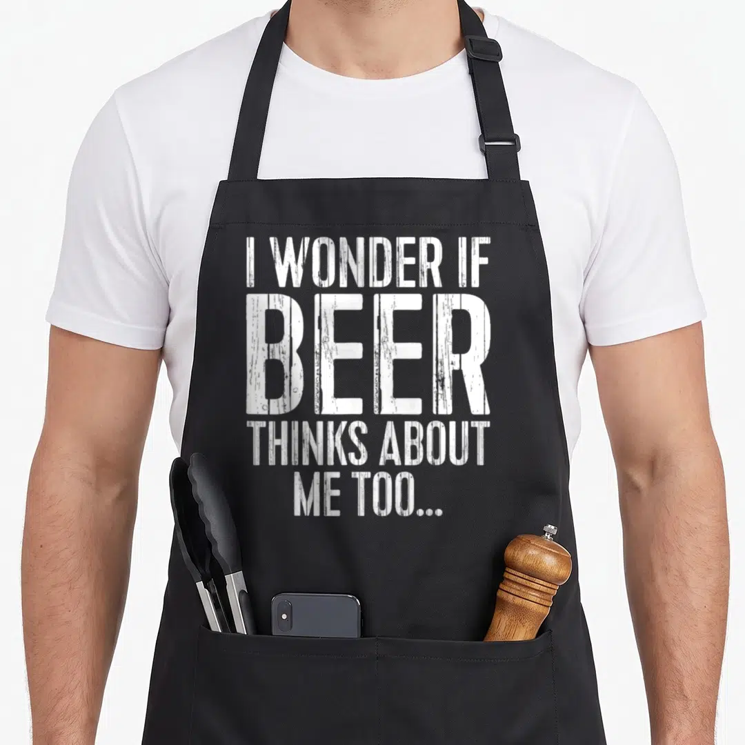 Wonder beer apron - White distressed typography reading I wonder if beer thinks about me too on grey background — shown on a black cotton canvas apron against a white background