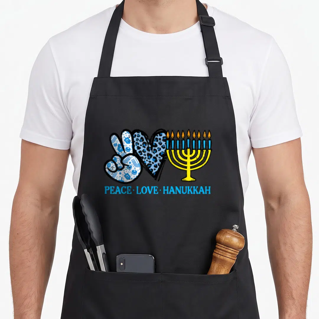 Peace chanukah hanukkah apron - Peace sign with dreidels, leopard heart, yellow menorah, and blue text — shown on a black cotton canvas apron against a white background