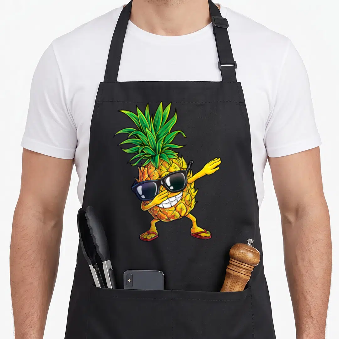 Dabbing pineapple apron - Cartoon pineapple wearing black sunglasses and red flip-flops in a dab pose — shown on a black cotton canvas apron against a white background