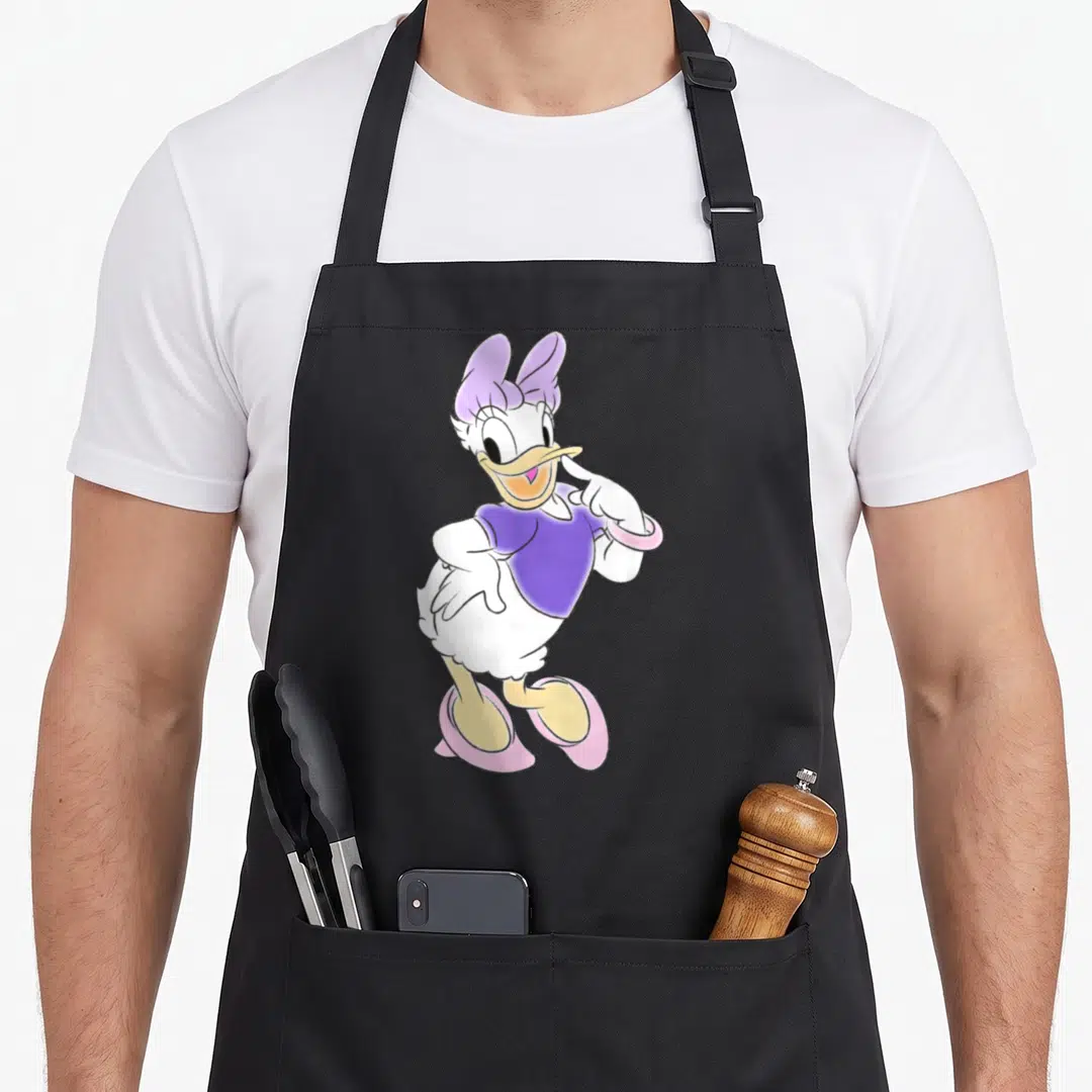 Unicorn daisy apron - Centered cartoon duck in purple top and pink shoes on white body — shown on a black cotton canvas apron against a white background
