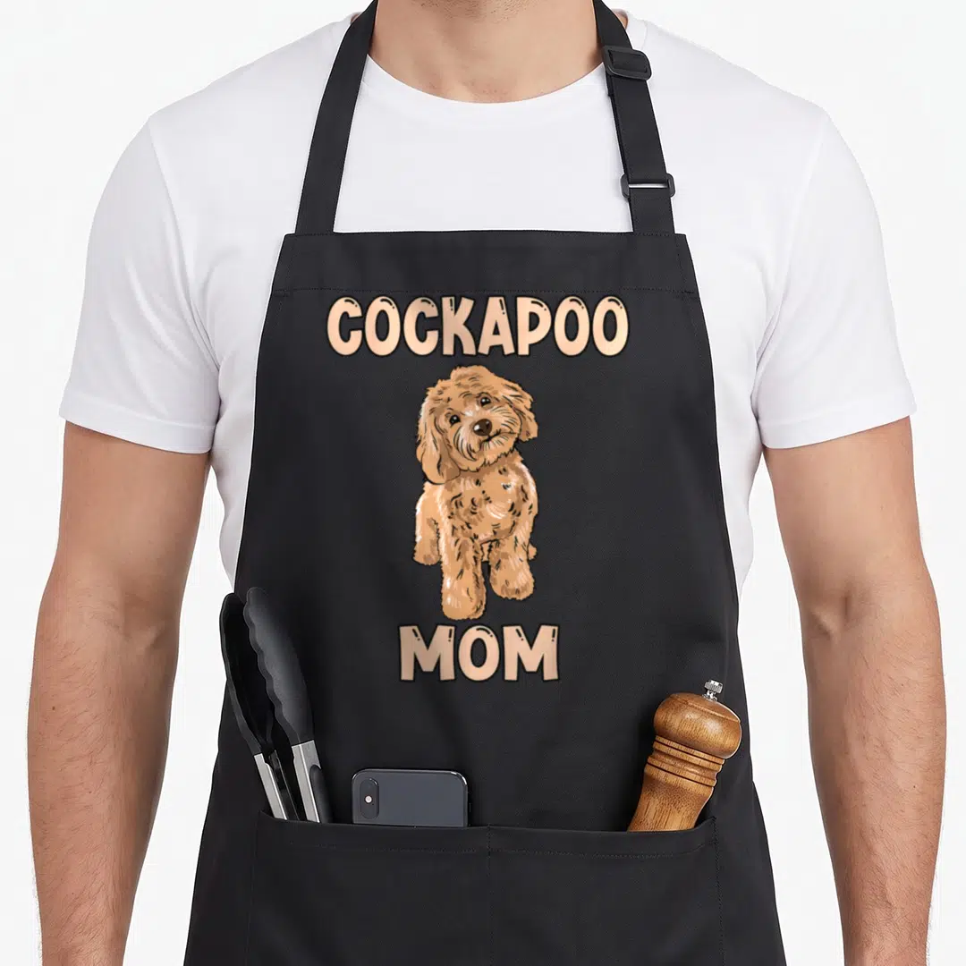 Dog cockapoo apron - Cartoon brown cockapoo dog between beige text reading COCKAPOO MOM — shown on a black cotton canvas apron against a white background