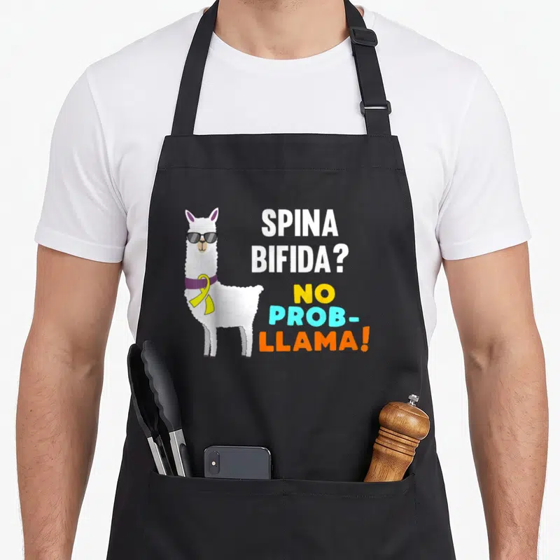Prob spina bifida awareness apron - White llama wearing sunglasses and ribbon next to stacked text reading SPINA — shown on a black cotton canvas apron against a white background