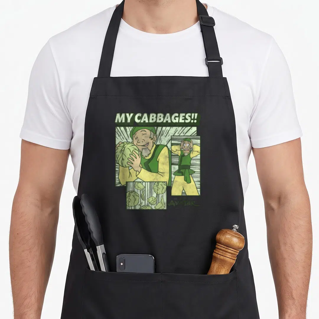 Merchant cabbage apron - Cabbage Man comic panels with MY CABBAGES!! text and AVATAR logo in green yellow beige — shown on a black cotton canvas apron against a white background