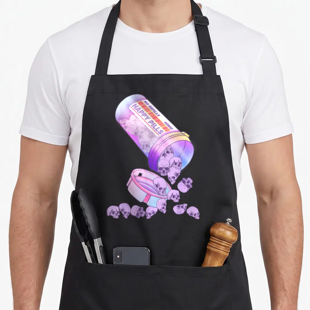 Pill goth apron - Tilted pastel bottle spilling skulls with NO REFILLS HAPPY PILLS 40MG label text — shown on a black cotton canvas apron against a white background