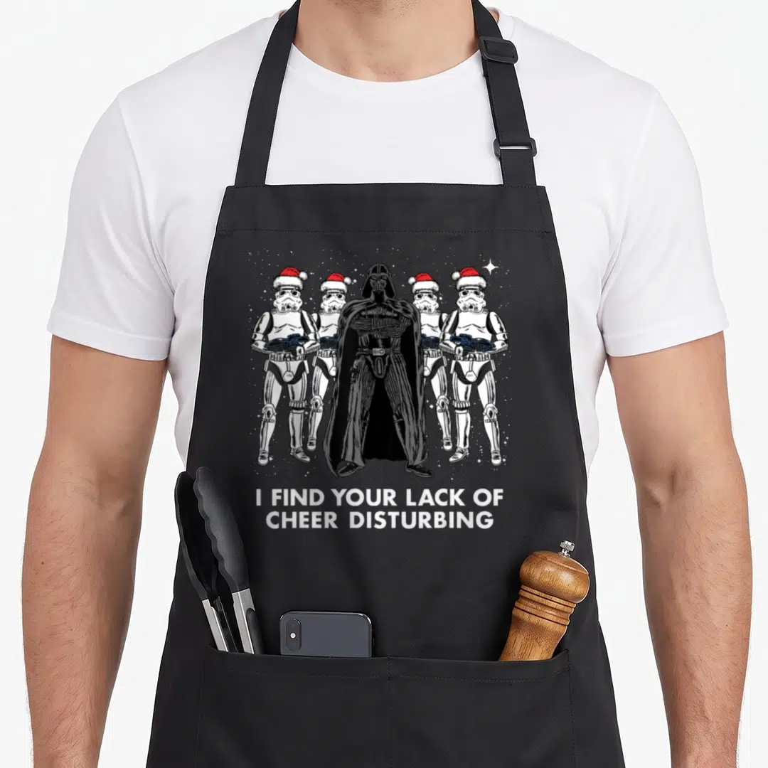 Vader christmas apron - Darth Vader and four stormtroopers in Santa hats with text I find your lack of cheer disturbing — shown on a black cotton canvas apron against a white background