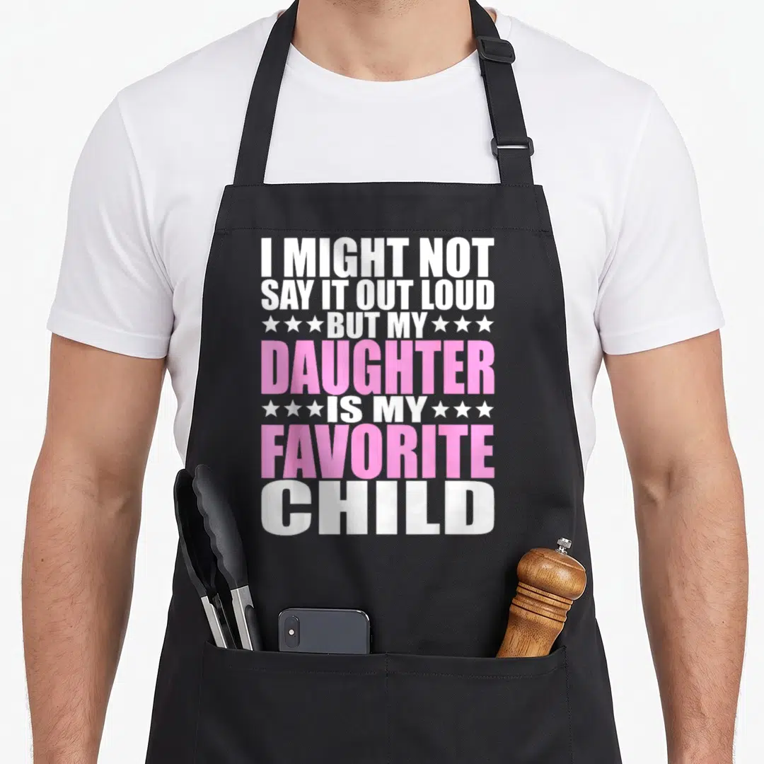 Daughter i love colorado apron - White and pink stacked text reading I might not say it out loud but my daughter is my — shown on a black cotton canvas apron against a white background