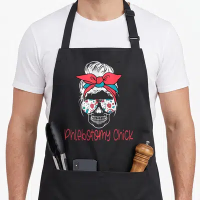 Phlebotomist blood apron - Cartoon skull with medical icon sunglasses and red bow above Phlebotomy Chick text — shown on a black cotton canvas apron against a white background