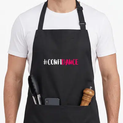 Confidance dancing apron - #CONFIDANCE hashtag in white and pink brush lettering — shown on a black cotton canvas apron against a white background