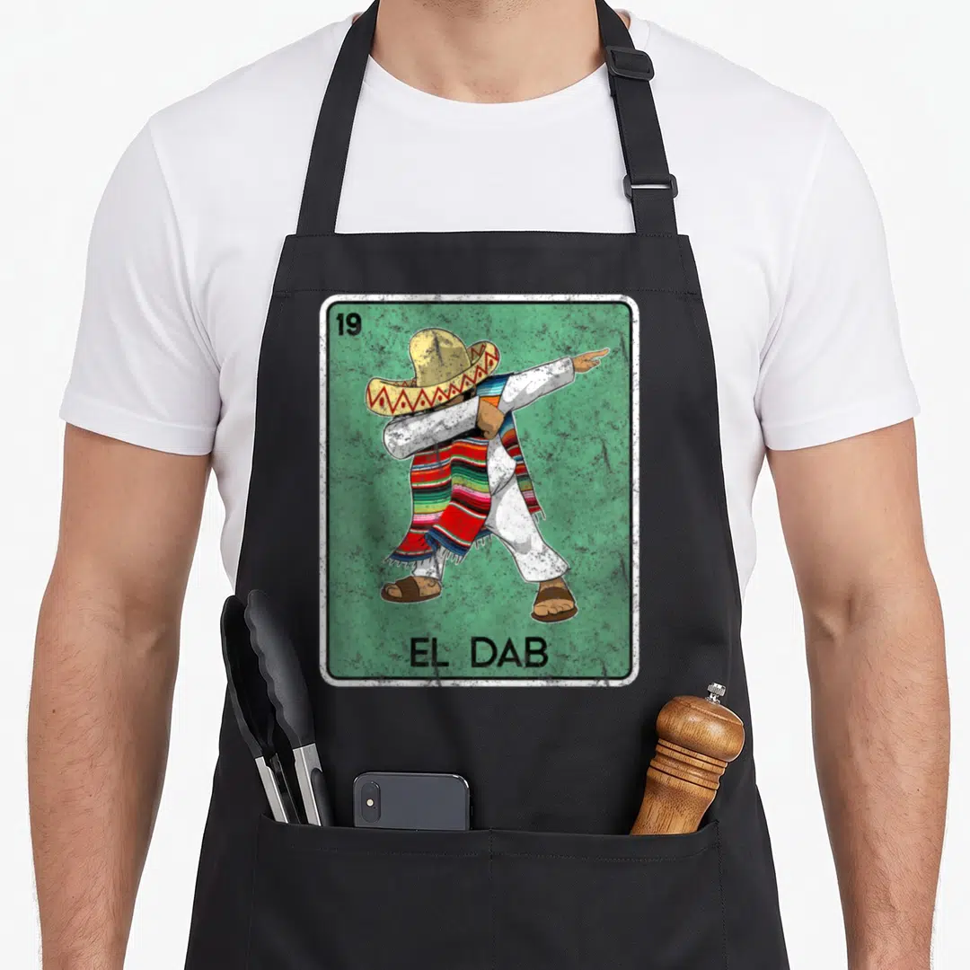 Card dab apron - Man in sombrero and serape dabbing on green card with EL DAB text — shown on a black cotton canvas apron against a white background