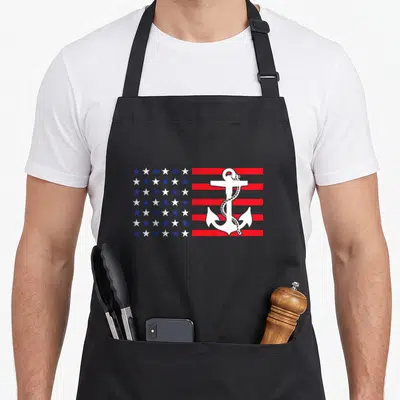 Anchor patriotic apron - White anchor and rope over red white blue star and stripe pattern — shown on a black cotton canvas apron against a white background