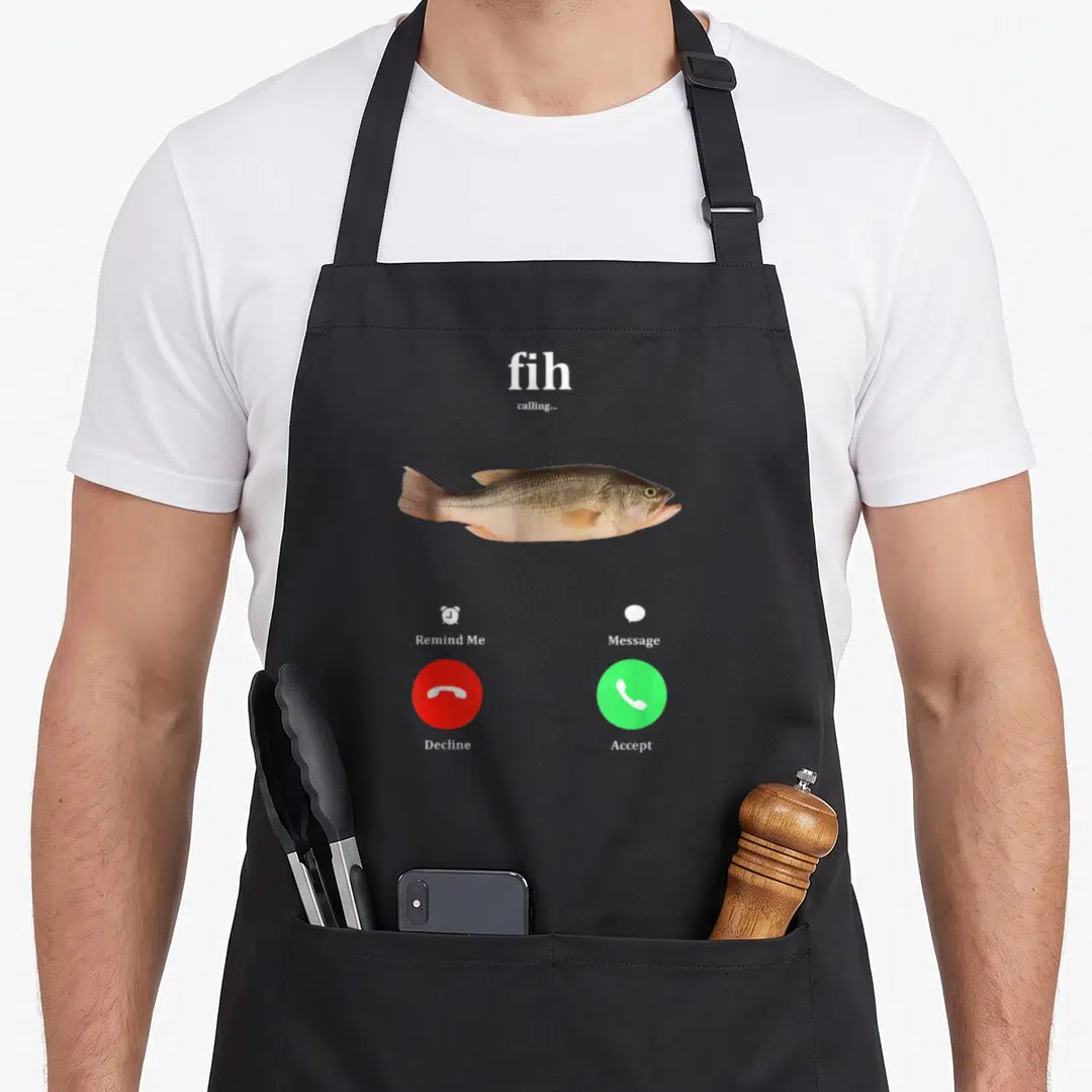 Calling fish apron - Smartphone call screen with brown fish, red decline button, green accept button, and white text — shown on a black cotton canvas apron against a white background