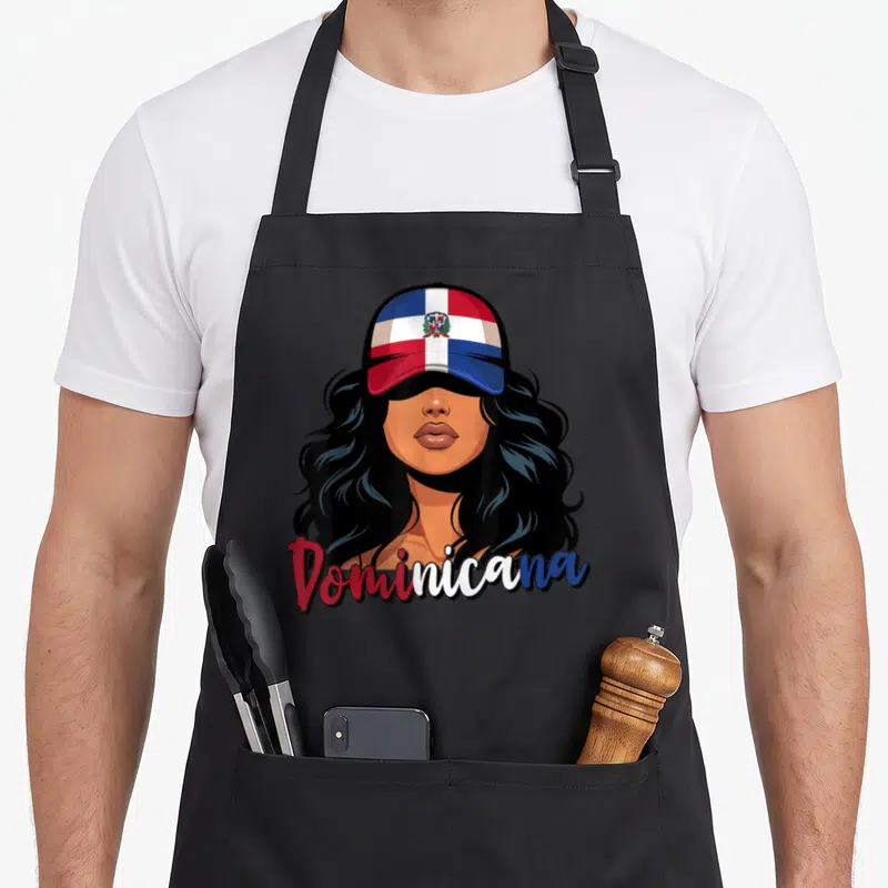 Proud dominican apron - Cartoon woman in red white blue flag cap with Dominicana script below — shown on a black cotton canvas apron against a white background