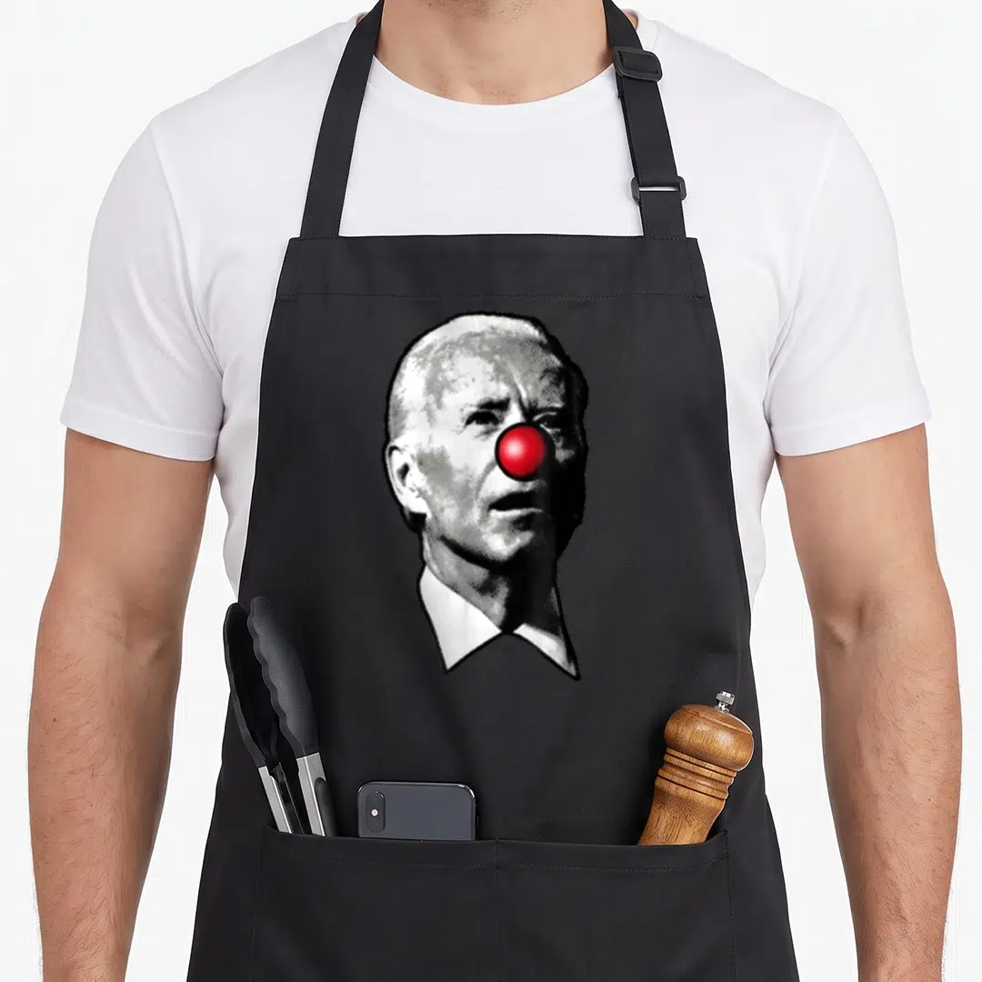 Show clown aprons - Grayscale man portrait with bright red clown nose printed on canvas — shown on a black cotton canvas apron against a white background