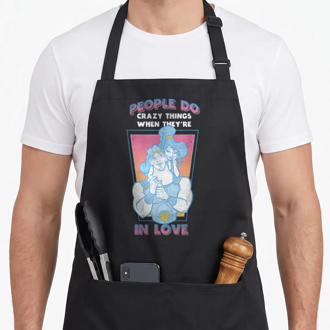 Hercule valentine's day apron - Cartoon couple in blue and pink with text PEOPLE DO CRAZY THINGS WHEN THEY'RE IN LOVE — shown on a black cotton canvas apron against a white background