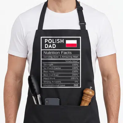 Nutrition polish kitchen aprons - Grey nutrition label reading Polish Dad with flag and values like 1001% Hard Work — shown on a black cotton canvas apron against a white background