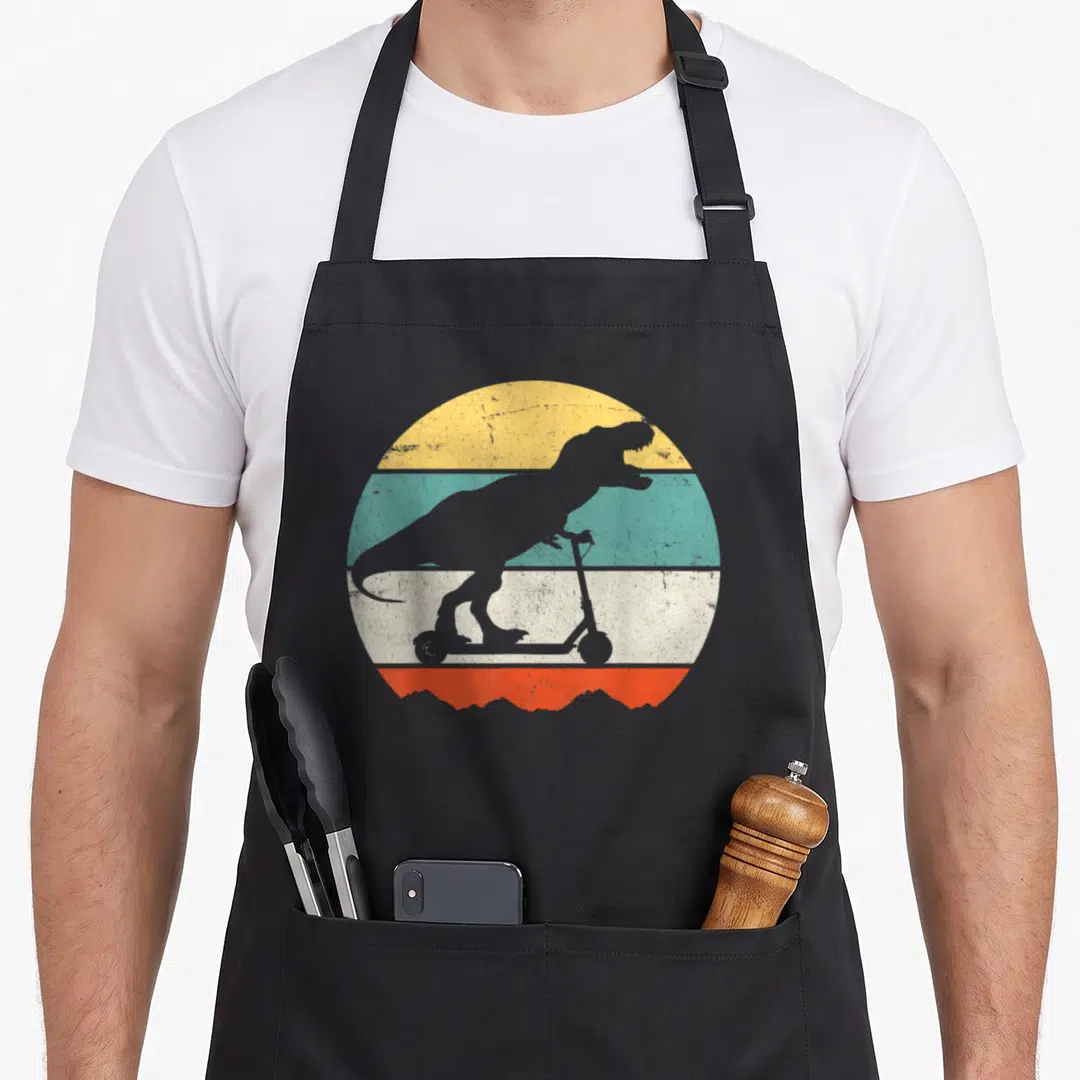 Vintage scooter apron - Grey T-Rex silhouette on scooter over yellow teal beige orange striped circle — shown on a black cotton canvas apron against a white background