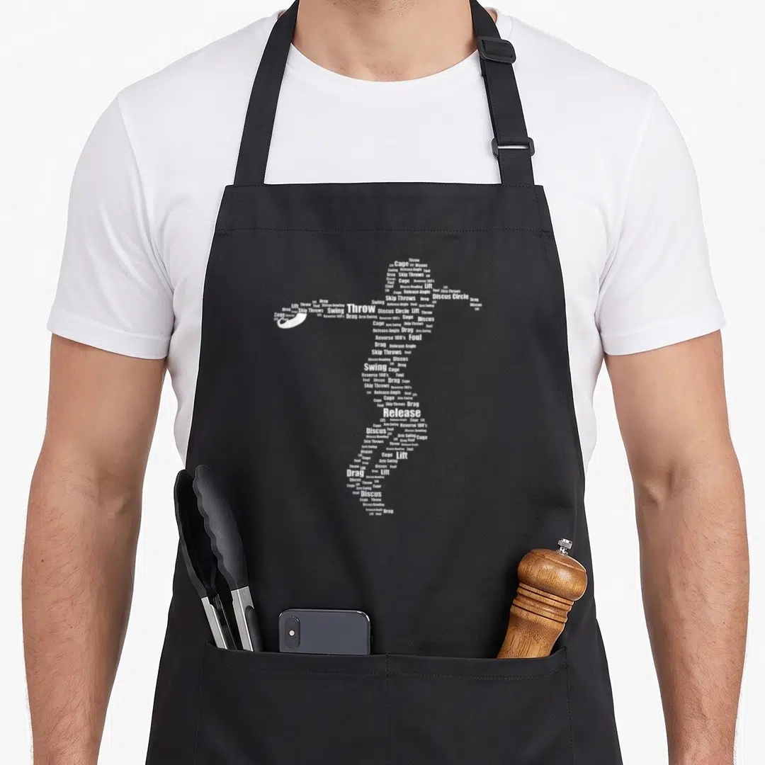 Technique throwers apron - White typographic silhouette of a discus thrower formed by words like swing, release angle — shown on a black cotton canvas apron against a white background