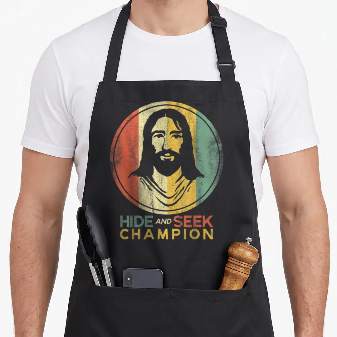 Freethinker science apron - Grey Jesus silhouette in red beige gold green teal striped circle with HIDE AND SEEK — shown on a black cotton canvas apron against a white background