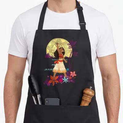 Fiti princess apron - Cartoon woman holding green stone in front of yellow sun with purple palms and flowers — shown on a black cotton canvas apron against a white background