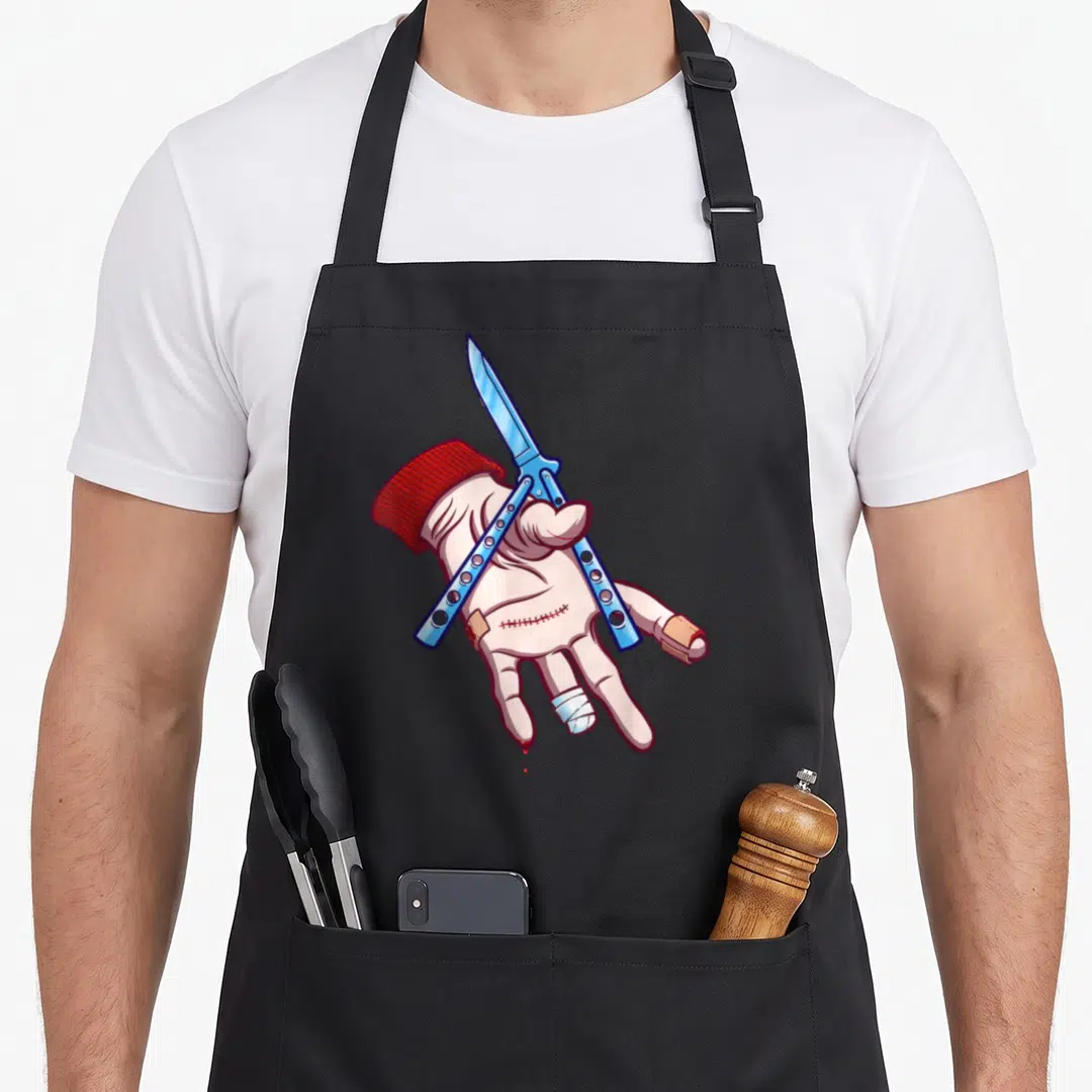 Kgullholmen dark grey apron - Cartoon hand holding blue butterfly knife with bandages and red blood drops — shown on a black cotton canvas apron against a white background