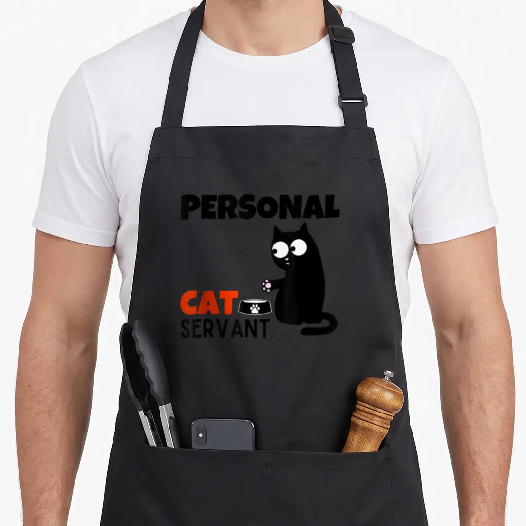 Personal funny cat aprons - Cartoon black cat next to Personal Cat Servant text and food bowl — shown on a black cotton canvas apron against a white background