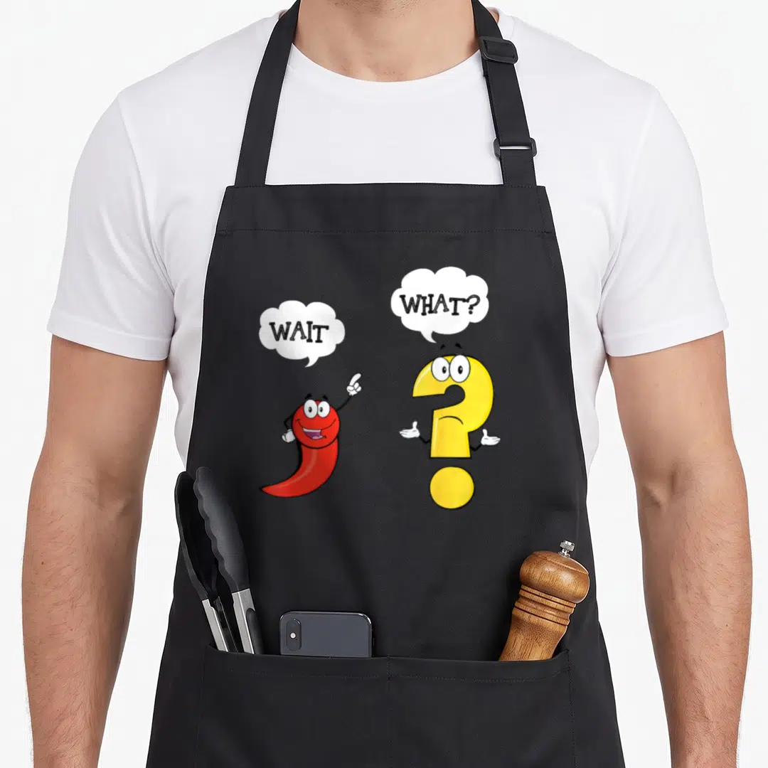 Wait english teacher apron - Red chili pepper and yellow question mark cartoon characters with speech bubbles reading — shown on a black cotton canvas apron against a white background