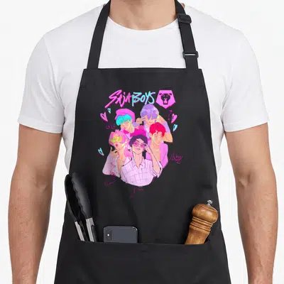 Saja trend apron - Saja Boys text lion icon five men cartoon pink purple blue names BB Abby Jinu Rumat hearts — shown on a black cotton canvas apron against a white background