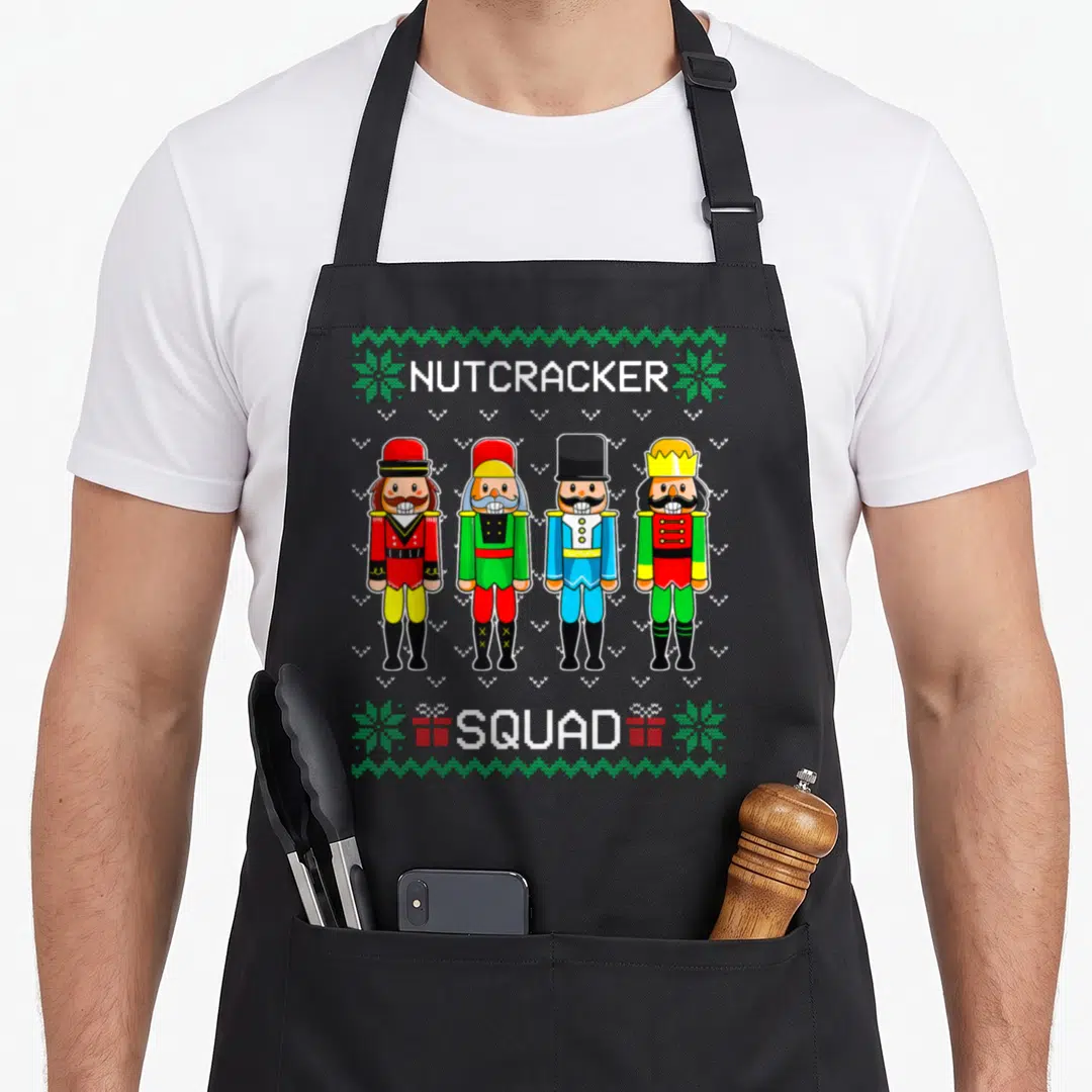 Dance christmas nutcracker apron - Four pixel art nutcracker soldiers in red green blue yellow with NUTCRACKER SQUAD — shown on a black cotton canvas apron against a white background