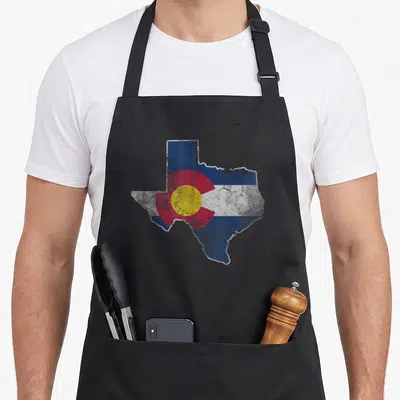 Texas colorado apron - Distressed Texas map shape filled with Colorado flag blue red yellow white pattern — shown on a black cotton canvas apron against a white background