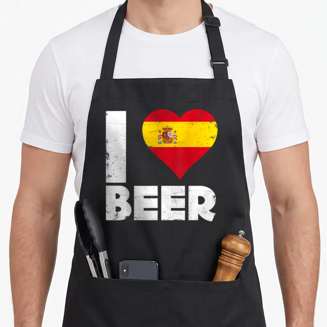 Beer spanish aprons - Distressed I BEER text with Spanish flag heart — shown on a black cotton canvas apron against a white background