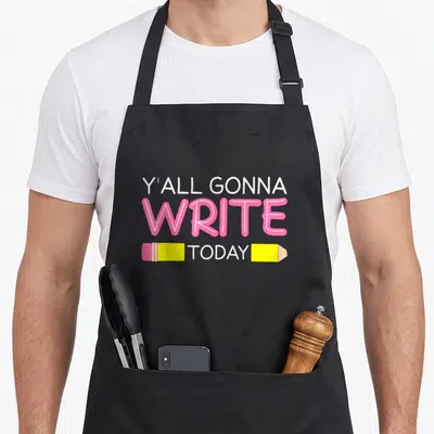 Yall teacher apron - Stacked text Y'all Gonna Write Today with split yellow pencil framing today — shown on a black cotton canvas apron against a white background