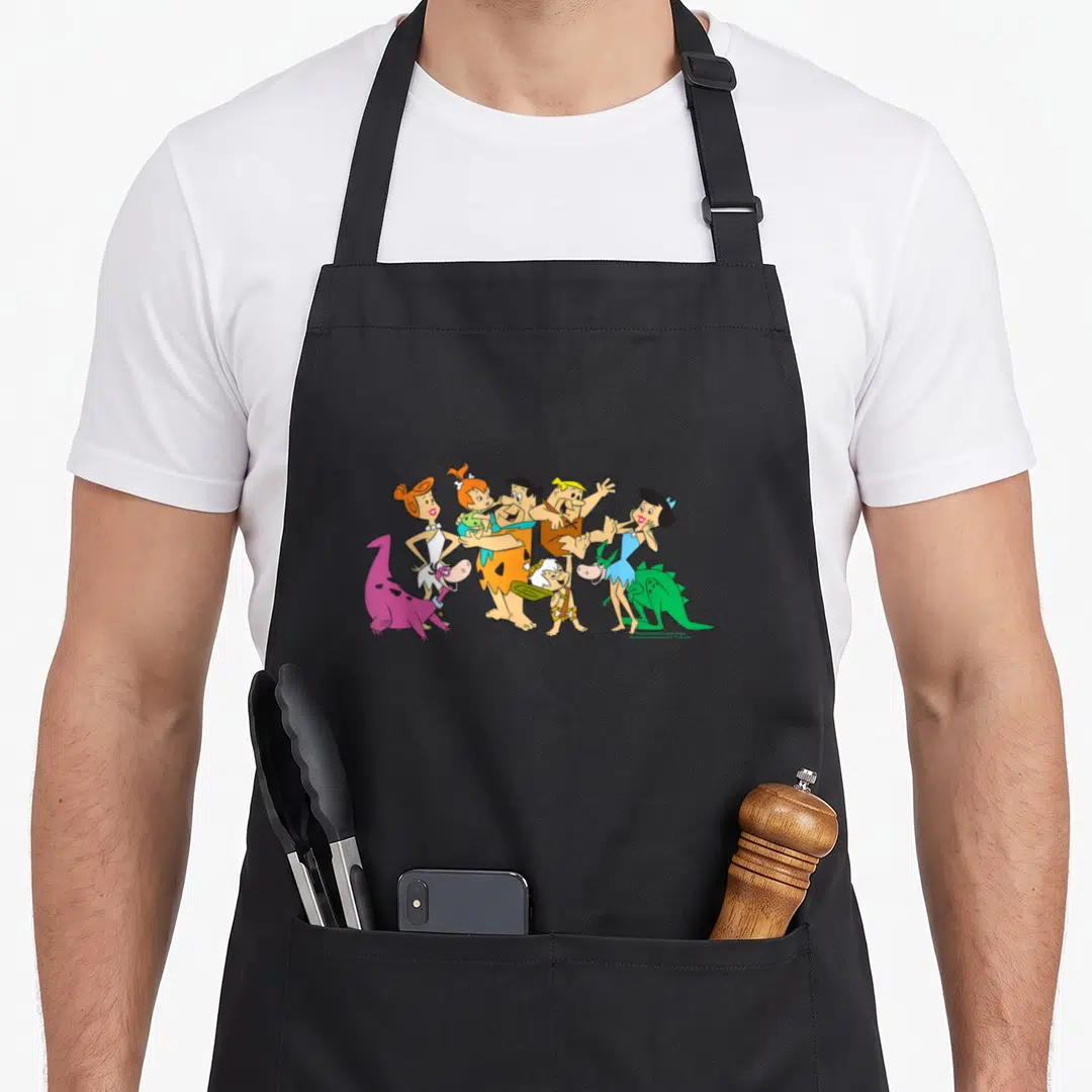 Fred novelty apron - Flintstones family cartoon group photo in orange blue purple green brown colors — shown on a black cotton canvas apron against a white background