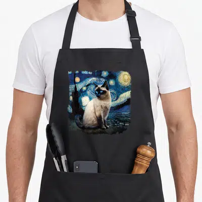 Van cute cat aprons - Realistic Siamese cat sitting before a swirling blue night sky with yellow stars and a dark — shown on a black cotton canvas apron against a white background